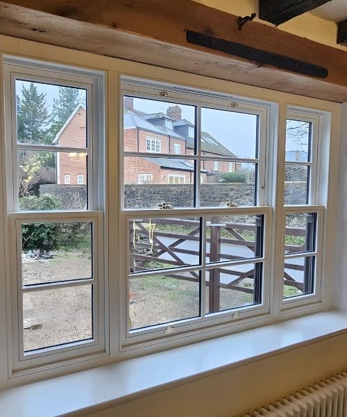 Interior view of white-painted timber sash windows showing dual colour paint option with white inside and darker exterior finish.