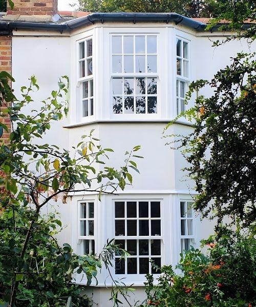 View oif Georgian style glazing bars wooden sash window from a garden